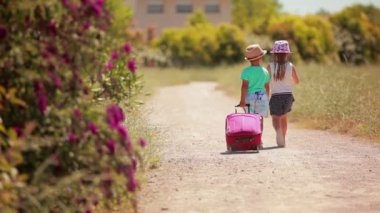 Şapkalı sevimli çocuklar yol boyunca yavaşça yürüyorlar.