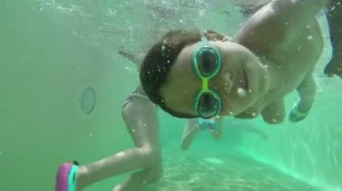 Çocuk suyun altında yüzüyor ve havuzun dibinde kıvranıyor.