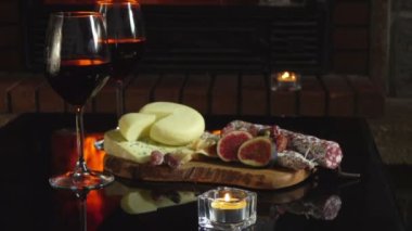 Tahtanın yanında iki kadeh kırmızı şarap ve çeşitli aperatifler duruyor. 