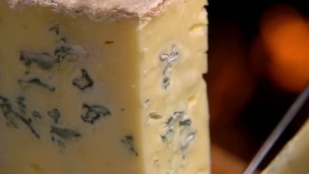 Close-up of a piece of blue Roquefort on a background of fireplace — Stock Video
