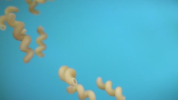 Trockene Pasta cellentani fliegt diagonal auf dem himmelblauen Hintergrund — Stockvideo