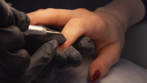 Close-up van manicure handen in de zwarte handschoenen verwijderen van de nagel gel gellak — Stockvideo