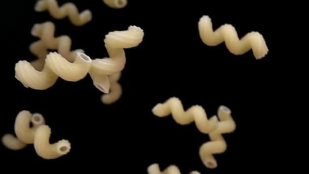 Trockene Pasta cellentani fliegt diagonal auf schwarzem Hintergrund — Stockvideo