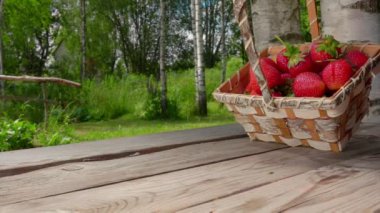 Masanın ahşap yüzeyinde büyük lezzetli çilekler zıplıyor.