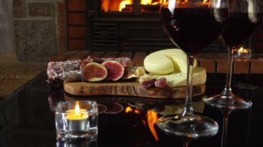 Siyah masada çeşitli aperatiflerle kırmızı şarap kadehleri duruyor.