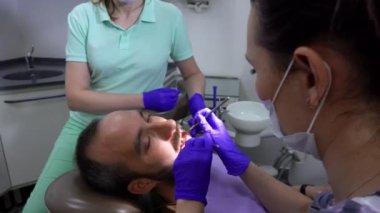  Dişçi erkek bir hastanın dişlerini muayene ediyor.