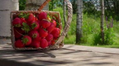 Sepet düşüyor ve lezzetli çilekler masanın üstüne düşüyor.