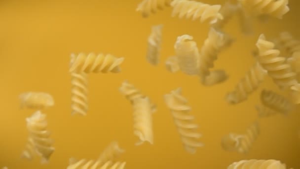 Suché těstoviny fusili pádu a otáčení diagonálně na žlutém pozadí — Stock video