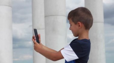 Neşeli çocuk telefonda selfie çekiyor.