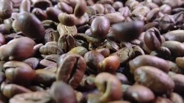 Kavrulmuş Arabika kahve çekirdeklerinin yakın çekim görüntüsü düşüyor ve dönüyor