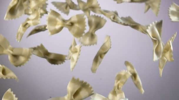 Macarrão listrado italiano Farfalle está voando sobre um fundo branco — Vídeo de Stock