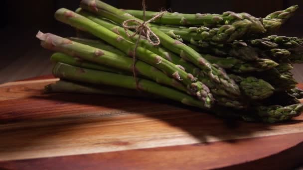 Banc de lance d'asperges vertes roulant sur une planche de bois — Video