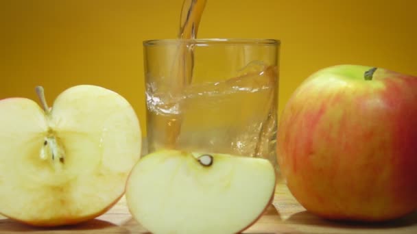 Délicieux jus de pomme frais est versé dans un verre sur le fond jaune — Video