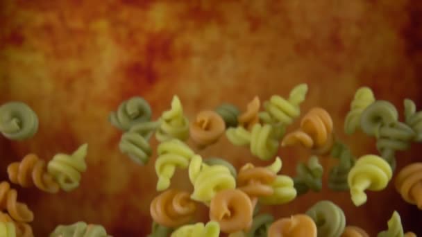 Droge kleurige pasta Conchiglie rigate vliegen op een gele oker achtergrond — Stockvideo