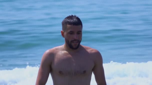 Jeune homme beau marche hors de l'eau de la mer surf — Video