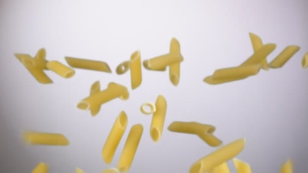 Penne de macarrão italiano seco voando sobre um fundo branco — Vídeo de Stock