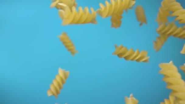 Pastas secas fusili volando diagonalmente sobre el fondo azul cielo — Vídeos de Stock