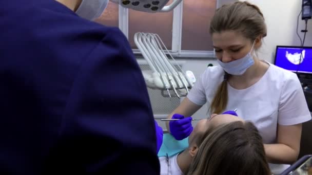 De vrouwelijke tandarts controleert de tanden van de patiënt om tandheelkundige probleem te begrijpen — Stockvideo