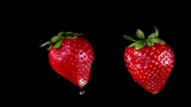 Çilekler siyah zemin üzerinde çarpışıyor yükselen su damlaları