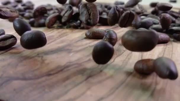 Primer plano de granos de café arabica tostados cayendo sobre la textura de madera — Vídeo de stock