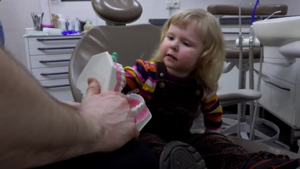 A fogorvos megtanít egy kislányt fogat mosni fogkefével. — Stock videók