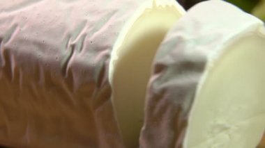 Sebze arkaplanında bıçakla kesilmiş Maure de Touraine peyniri.