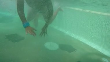 Çocuk yüzüyor ve ellerini suyun altında sallıyor.