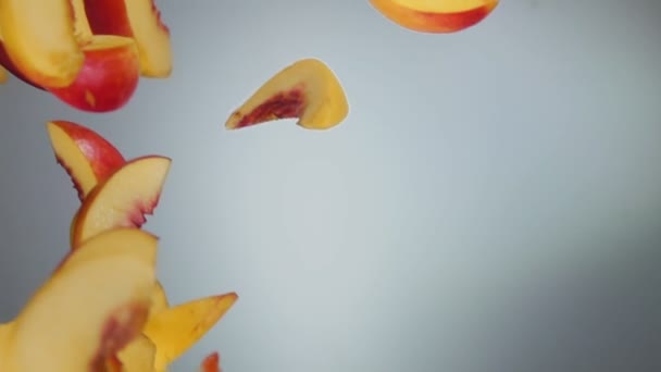 Nahaufnahme der frischen Pfirsichscheiben, die diagonal auf den weißen Hintergrund fallen — Stockvideo