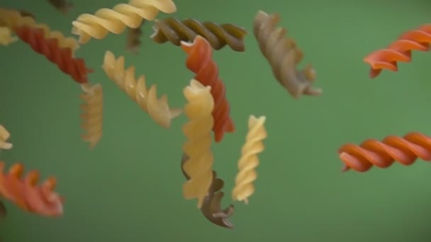 Ξηρό χρώμα fusili ζυμαρικά που υπάγονται διαγώνια σε ένα πράσινο φόντο — Αρχείο Βίντεο
