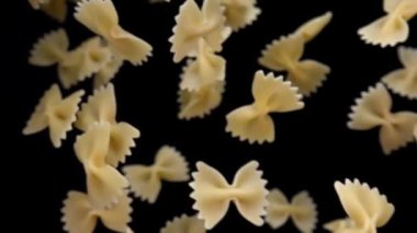  Farfalle makarnası siyah arka planda çapraz uçuyor.