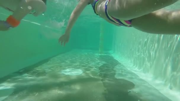 Kamera śledzi dzieci pływające pod wodą w basenie. — Wideo stockowe