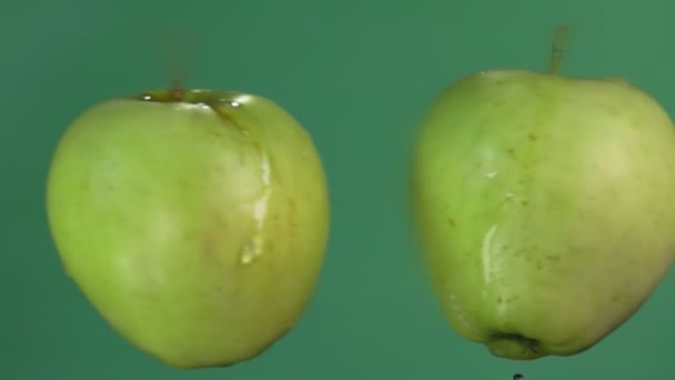 Duas maçãs verdes maduras estão levantando salpicos de água no fundo verde — Vídeo de Stock