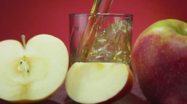 Taze elma suyu kırmızı arkaplanda bir bardağa dökülür.