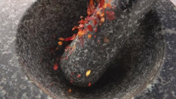 Pezzi di peperoncino piccante rosso stanno cadendo nel mortaio di pietra — Video Stock