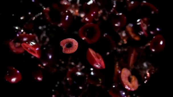 Metà ciliegie rimbalzano con spruzzi di succo su uno sfondo nero — Video Stock