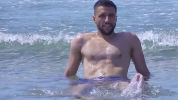 Jeune homme beau est assis dans la mer surf et profite de vacances — Video