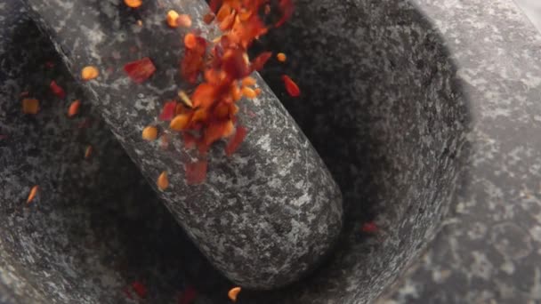 Pezzi di peperoncino rosso stanno cadendo nel mortaio di pietra — Video Stock