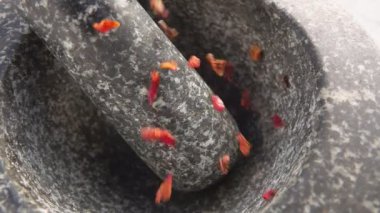 Kırmızı füme domates parçaları taş havan topuna dökülüyor.
