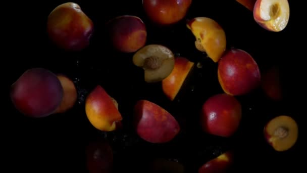 Половина свежего персика скачет на черном фоне — стоковое видео