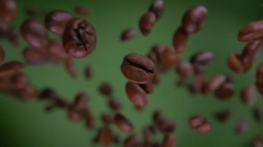 Yakın plan Arabika kahve çekirdekleri zeytin yeşili arka planda çapraz uçuyor.
