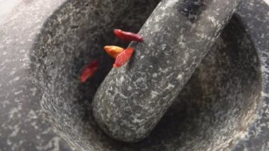 Kırmızı arnavut biberi kabuklarının taştan havana düşüşünü yakından çek.