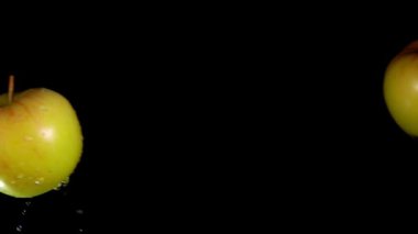 İki sarı elma birbirine doğru uçuyor ve siyah arka planda çarpışıyor.