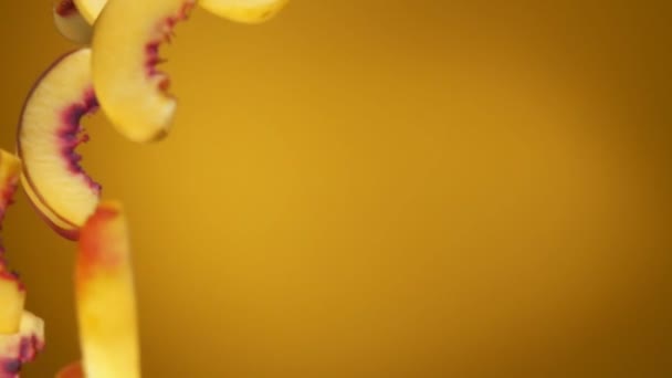 Kusy čerstvé zralé broskve padají úhlopříčně na žluté pozadí — Stock video