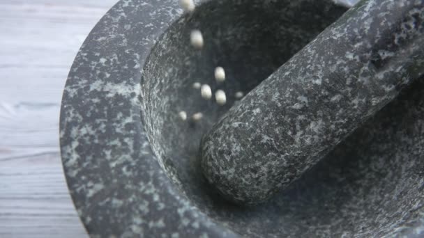 Close-up de boabe de piper alb care cad în mortarul de piatră gri — Videoclip de stoc