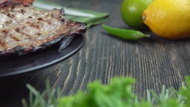 Тарелка с жареной белой рыбой на фоне лимонов и зелени — стоковое видео