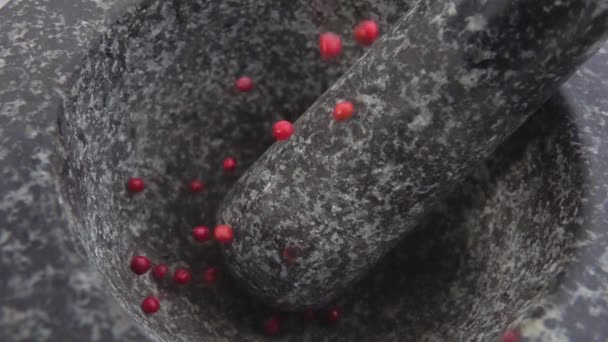 Los granos de pimienta roja están cayendo en el mortero de piedra gris — Vídeo de stock