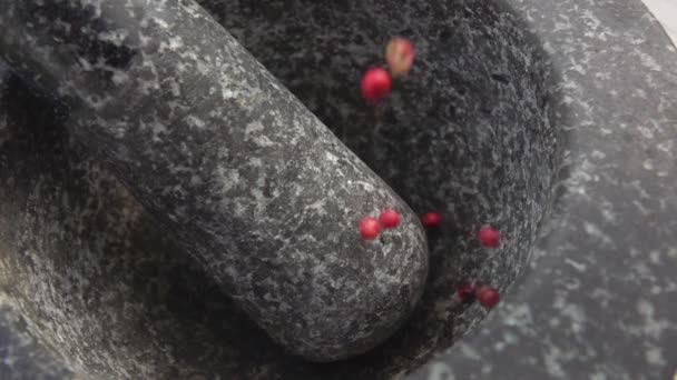 Grani di pepe rosso rosa stanno cadendo nella malta di pietra grigia — Video Stock