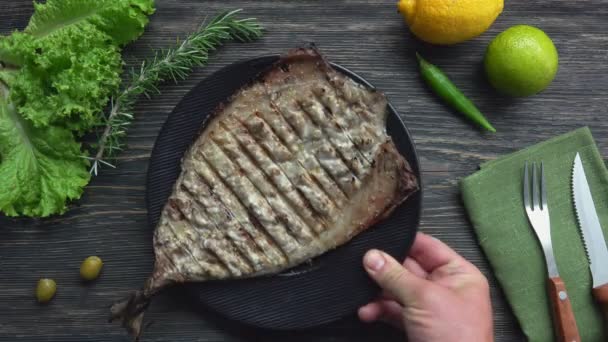 Vue de dessus de l'assiette avec un poisson blanc grillé juteux placé sur la table — Video