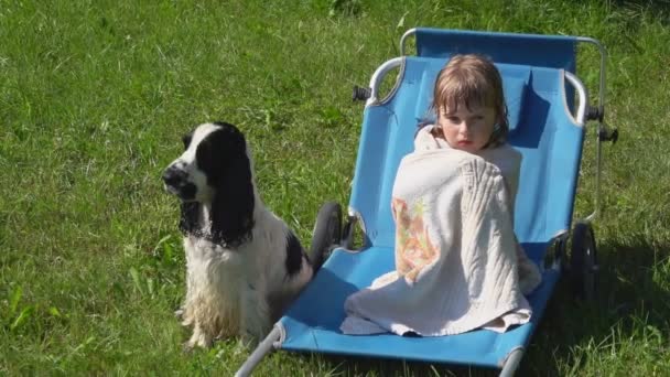 Ein kleines Mädchen sitzt im Strandkorb, eingewickelt in eine Handtuchdecke — Stockvideo