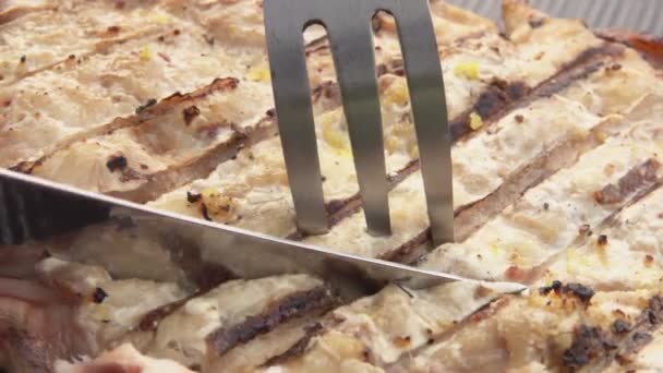 Super-aproape de un cuțit și furculiță luând o bucată de pește alb la grătar gustos — Videoclip de stoc